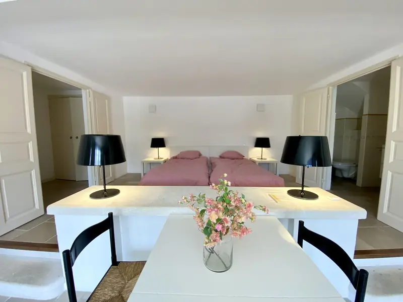 Het slaapgedeelte met twee bedden, gezien vanaf de eettafel, met links de garderobe en rechts de badkamer