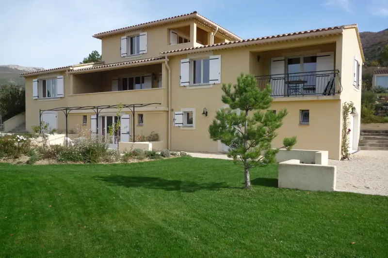 The west side of the villa above the lawn, with the studio's pergola and the apartment's loggia